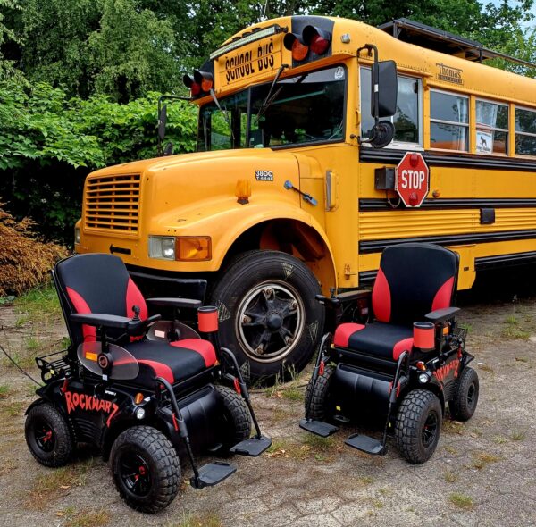 Foto von zwei E-Rollstühlen vor einem alten, amerikanischen Schulbus
